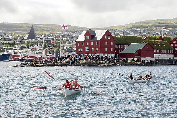 Two rowing boats after a competion in occasion of 'lavsoka festival in the city of Torshavn. In the background the red buildings of Tinganes. Island of Streymoy. Faroe Islands
