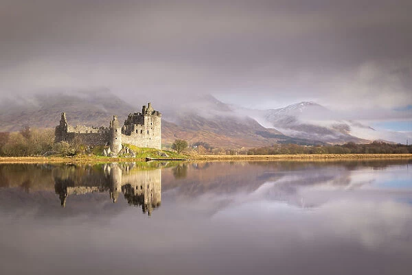The ruins of Kilchurn Castle reflected in Loch Awe at dawn on a misty morning in the