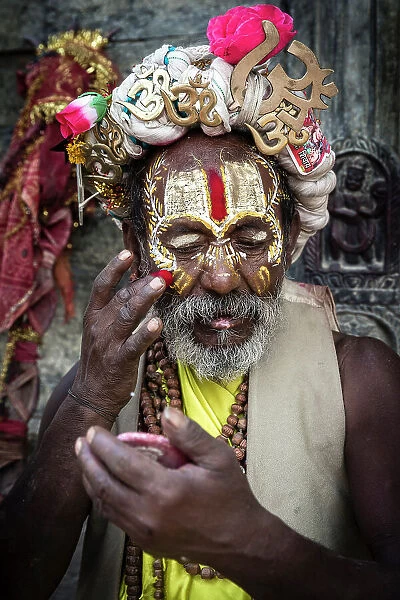 Sadhu (holy man) applying coloured powder at Pashupatinath Temple, Kathmandu, Nepal