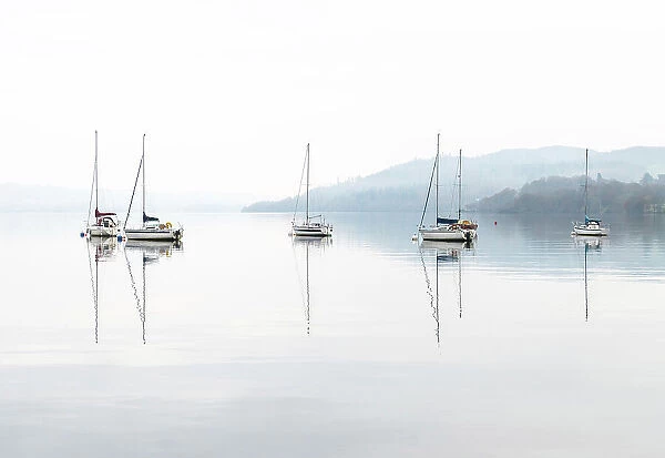 Sailing boats reflected in Windermere on a misty autumnal morning, Lake District National Park, Cumbria, England