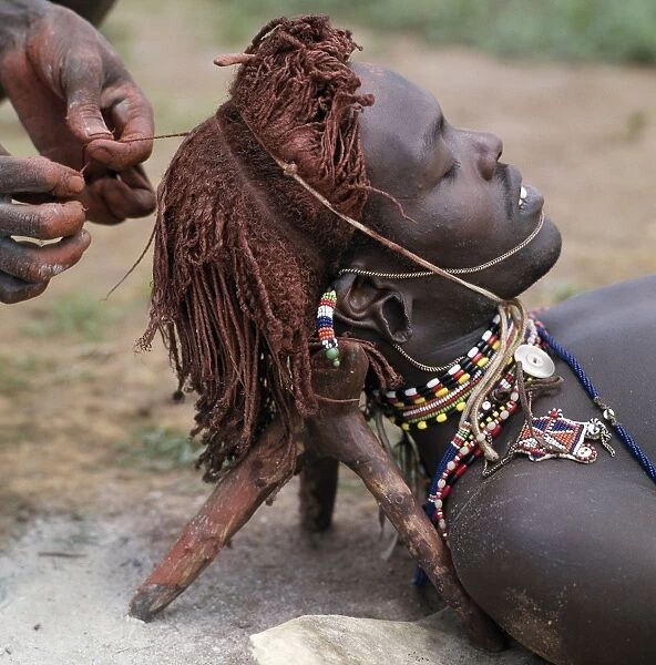A Samburu warrior has his Ochred hair braided by a friend