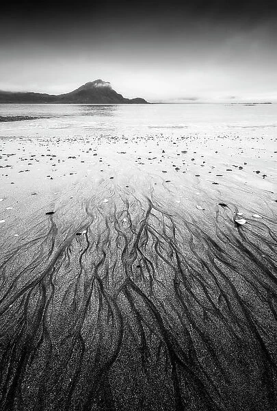 Sand patterns create an eye-catching foreground at Haukland beach on a gloomy summer morning. Lofoten Islands, Norway