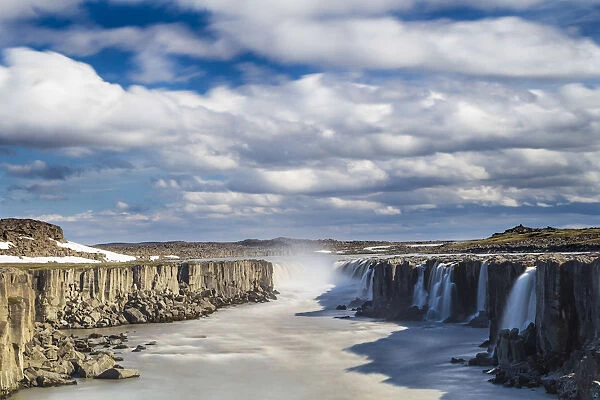 Scenic view of Selfoss waterfall amidst rocky cliffs against cloudy sky, Northeast