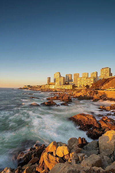 Seascape of residential high-rise buildings by rocky coast at sunset, Concon, Valparaiso Province, Valparaiso Region, Chile