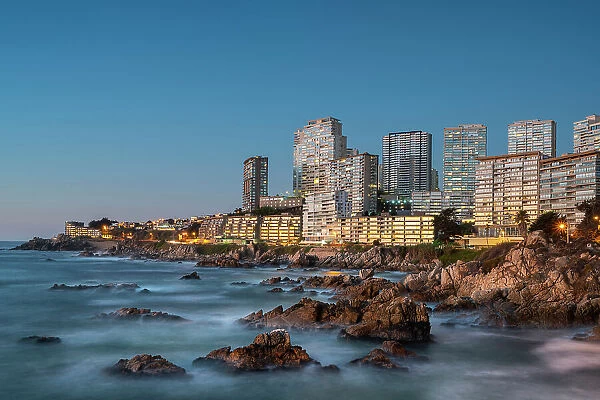 Seascape of residential high-rise buildings by rocky coast at twilight, Concon, Valparaiso Province, Valparaiso Region, Chile
