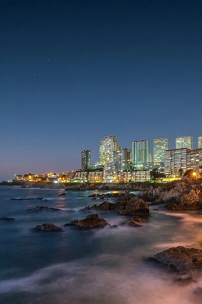 Seascape of residential high-rise buildings by rocky coast at twilight, Concon, Valparaiso Province, Valparaiso Region, Chile