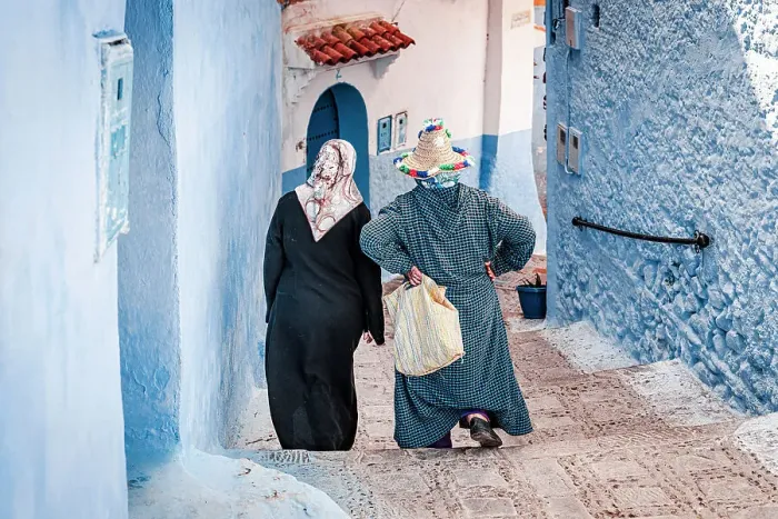 Framed Print : Senior women with hijab walking along the blue buildings of medina, Chefchaouen, Morocco
