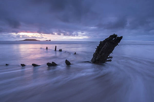 Shipwreck of the Helvetia on Rhossili Beach, looking towards Worms Head at sunset