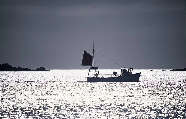 A silhouetted fishing boat passes the Eastern Isles