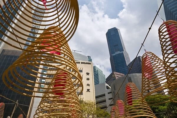Singapore, Singapore, Raffles Place. Spiral incense coils with city skyline in background at Wak Hai Cheng