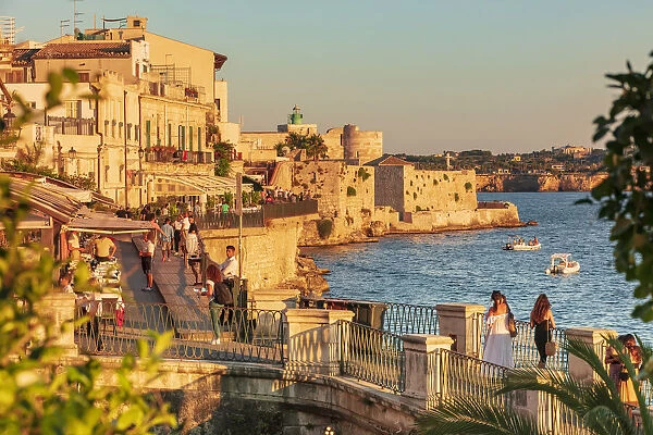 Siracusa, Sicily. People walking by the sea at sunset