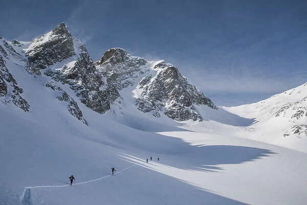 Ski mountaineers in Agnel valley, with the wind on the peaks. Engadina, Suisse