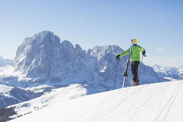 a skier is admiring the winter landscape in Val Gardena, with the Langkofel and Plattkofel