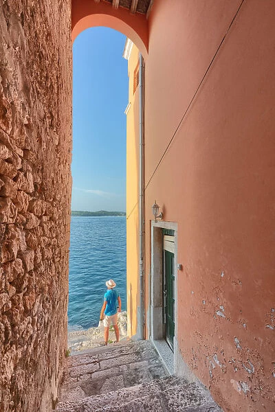 small arched opening overlooking the sea along the streets of Rovinj, tourist admires