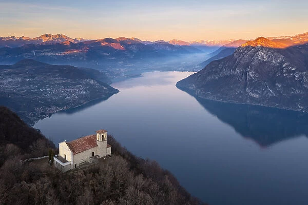 small church of Santuario della Santissima TrinitÔêÜÔÇá at the top of a mountain dominating Lake Iseo at sunset. Parzanica, Iseo Lake, Bergamo district, Lombardy, Italy