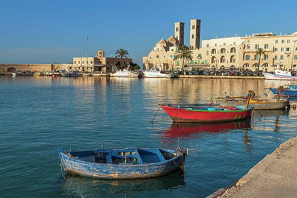 Small fishing boats in the harbour of Molfetta old town with the church in the background, Apulia, Italy