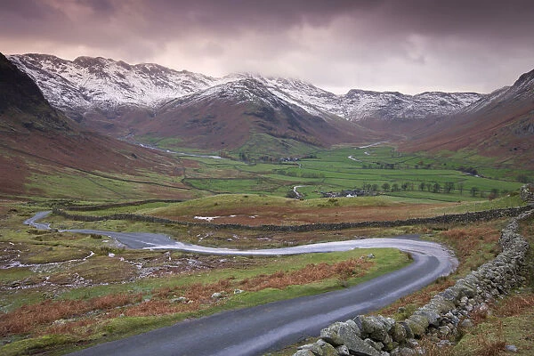 Small winding road leading into the Langdale Valley, surrounded by snow clad mountains