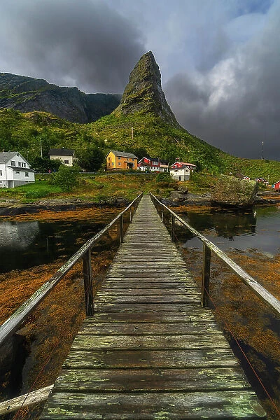 A small wooden bridge creates a great leading line towards the rugged peak and the colorful houses in Reine. Lofoten Islands, Norway