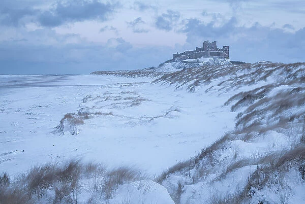 Snow covered beach and dunes on a wintry day at Bamburgh Castle in Northumberland, England. Winter (February) 2018