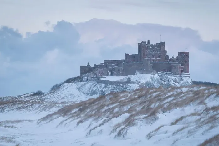 Framed Print : Snow covered beach and dunes on a wintry day at Bamburgh Castle in Northumberland, England. Winter (February) 2018