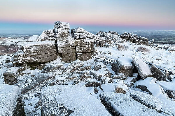 Snow and ice covered moorland at dawn on Belstone Tor in Dartmoor National Park, Devon, England. Winter (December) 2022