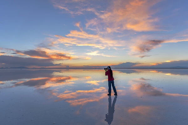 South America, Andes, Altiplano, Bolivia, Salar de Uyuni, woman taking pictures at sunset