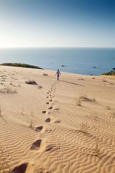 South America, Brazil, Ceara, Morro Branco, a man walks out towards the Atlantic Ocean