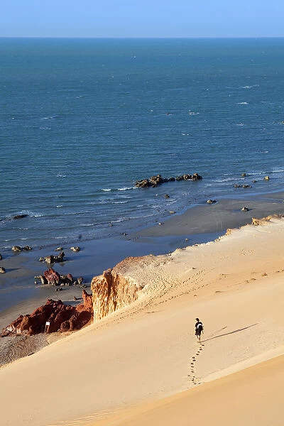 South America, Brazil, Ceara, Morro Branco, a photographer looks out over a long sandy