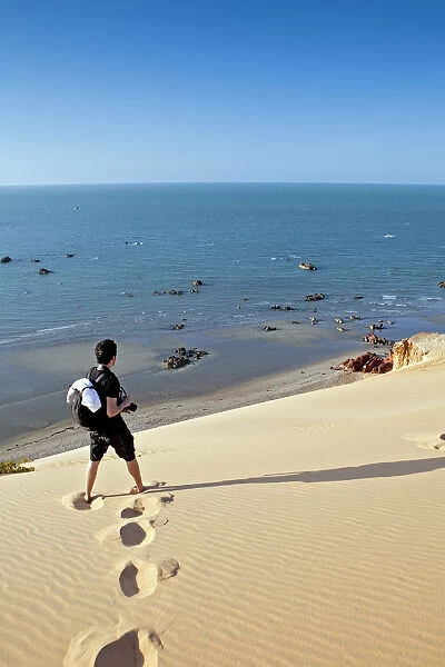 South America, Brazil, Ceara, Morro Branco, a photographer looks out over a long sandy