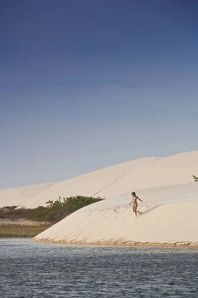 South America, Brazil, Maranhao, a woman in a bikini descends a dune in the Lagoa