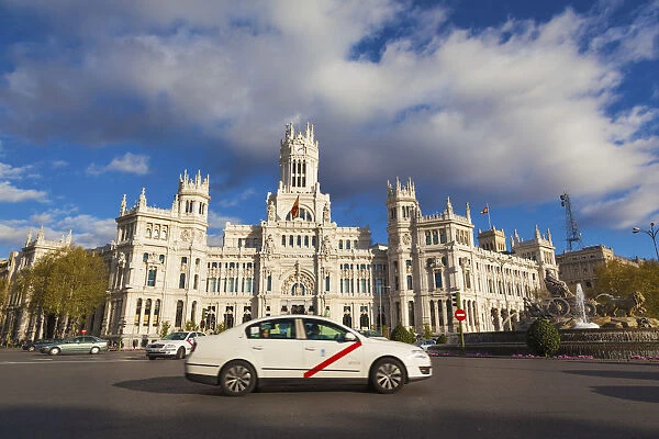 Spain, Madrid, taxi driving past Plaza de Cibeles with fountain and town hall building