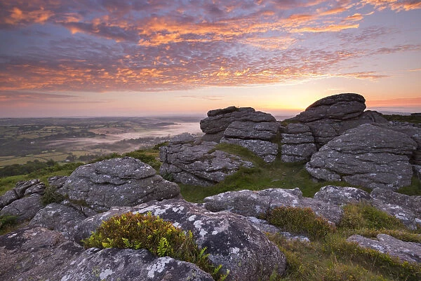 Spectacular sunrise above the granite tor on Meldon Hill, Dartmoor National Park, Devon
