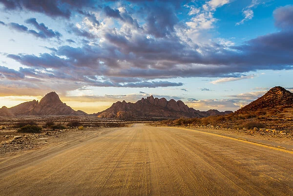 Spitzkoppe, Damaraland, Namibia, Africa. Gravel road to the granite peaks at sunset