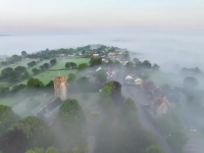 Framed Print : St Mary's Church and village emerging from morning mist at sunrise, Morchard Bishop, Devon, England. Summer (July) 2024 Framed Print : St Mary's Church and village emerging from morning mist at sunrise, Morchard Bishop, Devon, England. Summer (July) 2024
