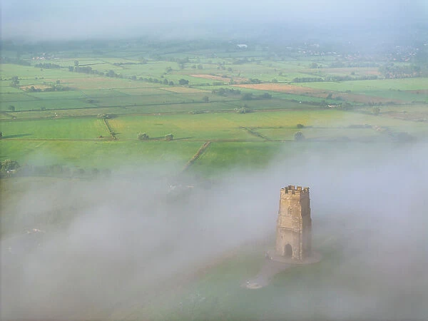 St Michael's Tower emerging from morning mist on Glastonbury Tor, Somerset, England. Summer (August) 2023