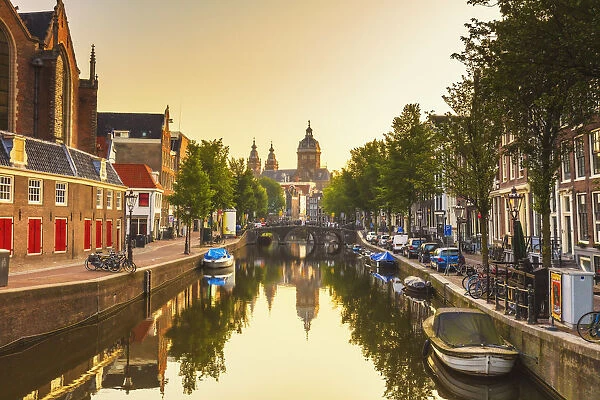 St. Nicholas church reflecting in the water canal at sunrise in Amsterdam