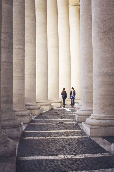 St Peters Square, Rome, Lazio, Italy. People walking among the colonnades