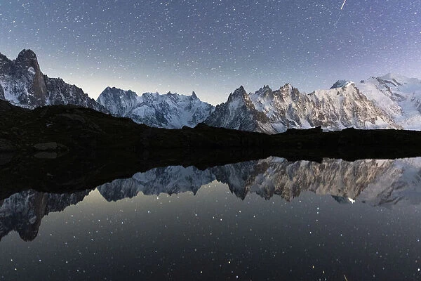 Starry night sky over Mont Blanc, Grand Jorasses and Aiguille Vert reflected in Lacs de Cheserys, Haute Savoie, France