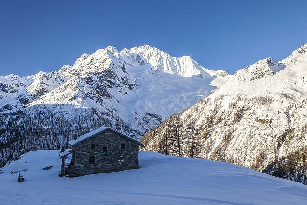 Stone hut at the foot of the snowy Monte Vazzeda, Alpe dell Oro, Valmalenco