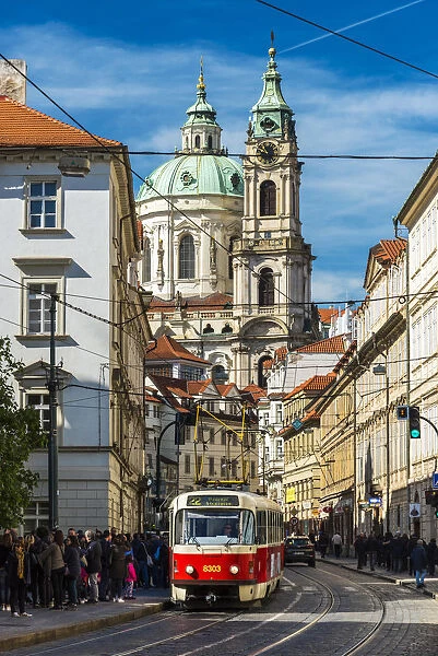Street in Mala Strana district with tram and St. Nicholas Church in the background