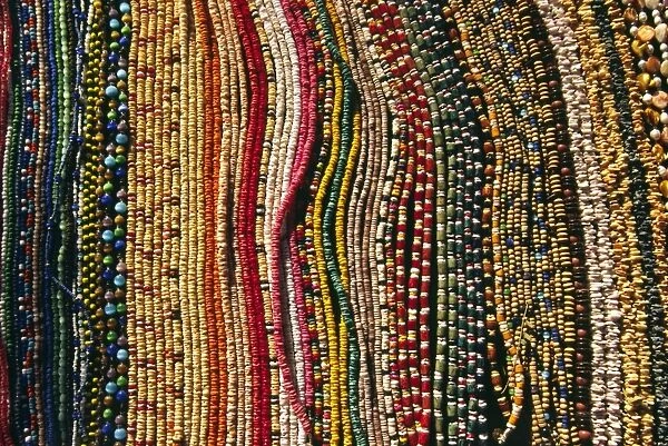 Strings of colourful beads are laid out for sale at
