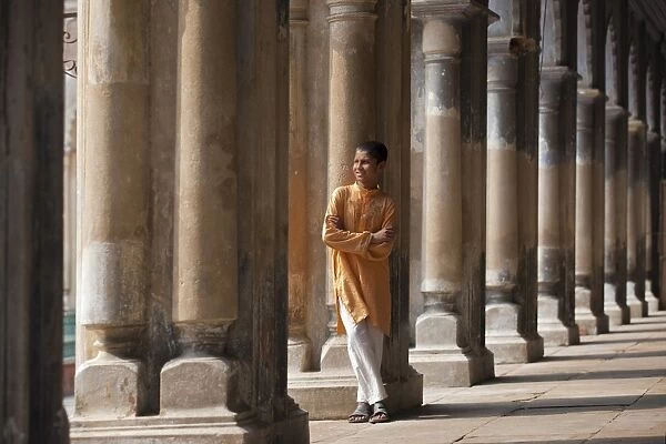 A student relaxes beside the pillars of the impressive Hugli Imambara building which was built in 1858 and is used as a school