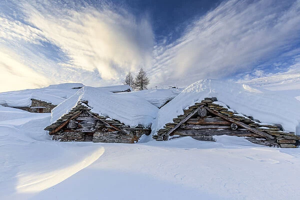 Stunning clouds at sunrise above traditional old huts in winter