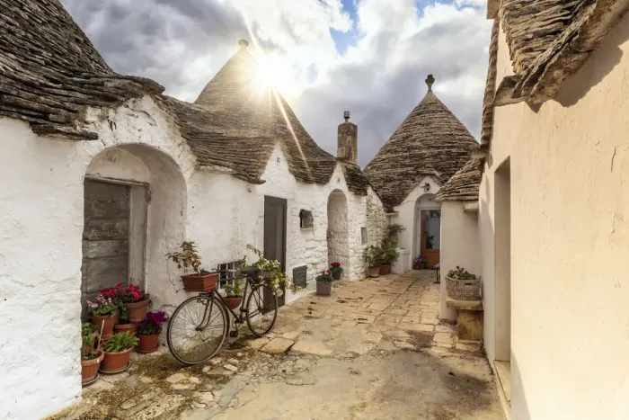 Framed Print : Sun light filters between clouds and illuminates trullo house