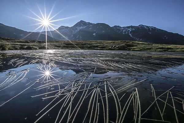 Sun rises on Peak Emet reflected in Lake Andossi Chiavenna Valley Spluga Valley