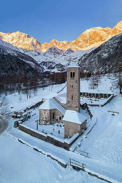 Sunrise in front of Monte Rosa from the old church of Macugnaga in winter. Valle Anzasca, Ossola, province of Verbania, Piedmont, italian alps, Italy