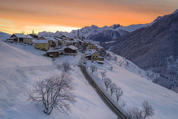 Sunrise over the empty road towards the village of Guarda after a winter snowfall