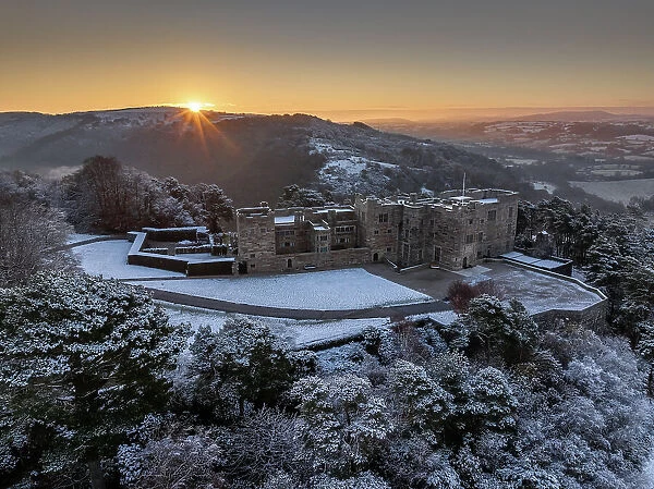 Sunrise over snow covered Castle Drogo on a chill winter morning, Dartmoor National Park, Devon, England. Winter (December) 2023