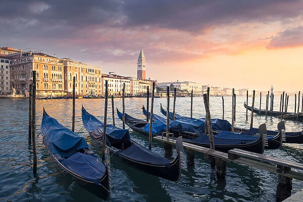 Sunset with gondolas and St. Mark belltower. Venice, Veneto, Italy