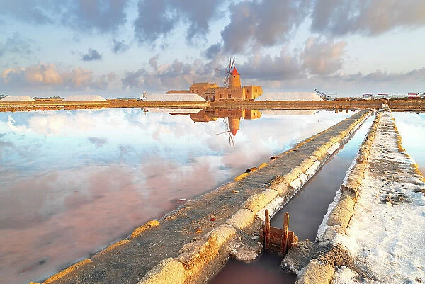 Sunset reflection at the salt flats with the old windmill, saline dello Stagnone, Marsala, Trapani province, Sicily, Italy